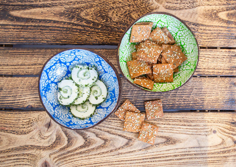 10 online Zwei verzierte Kokosnusschalen mit Crackern und Snacks auf Holzuntergrund